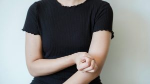 Femme tenant son bras au niveau du coude, douleur liée au tennis elbow