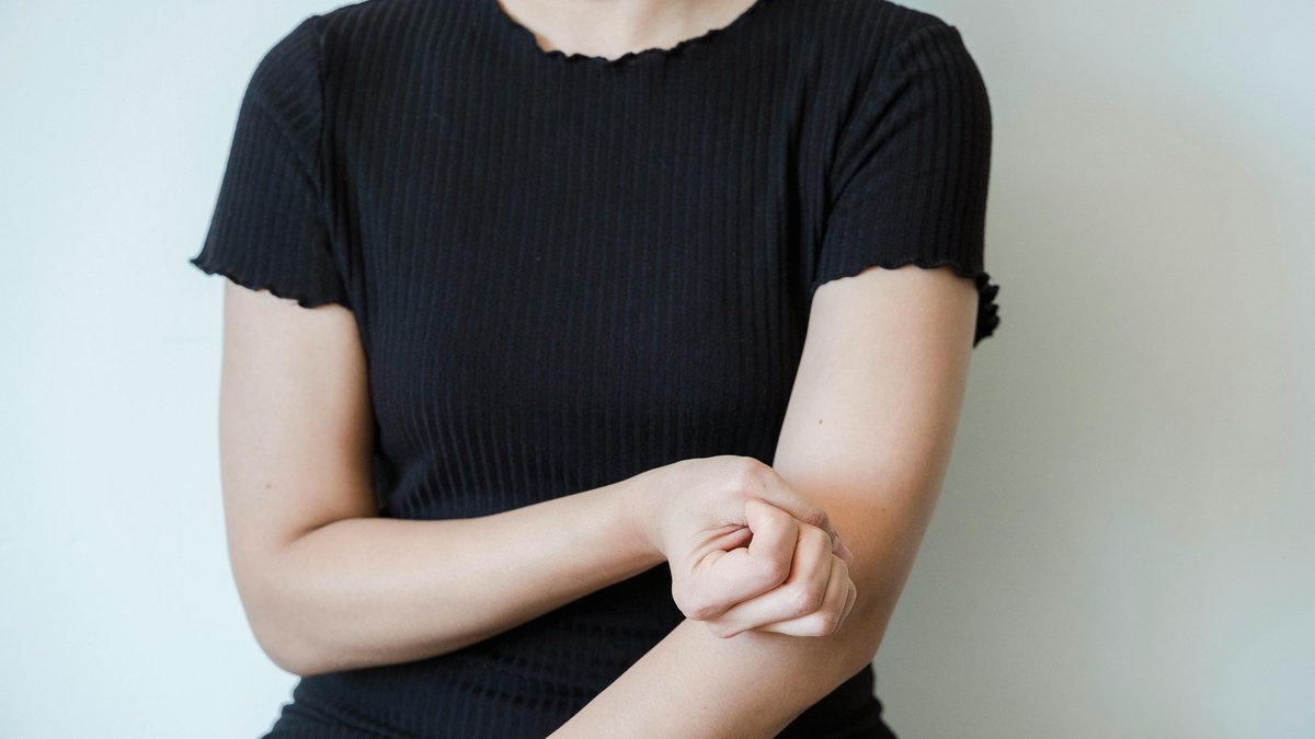 Femme tenant son bras au niveau du coude, douleur liée au tennis elbow