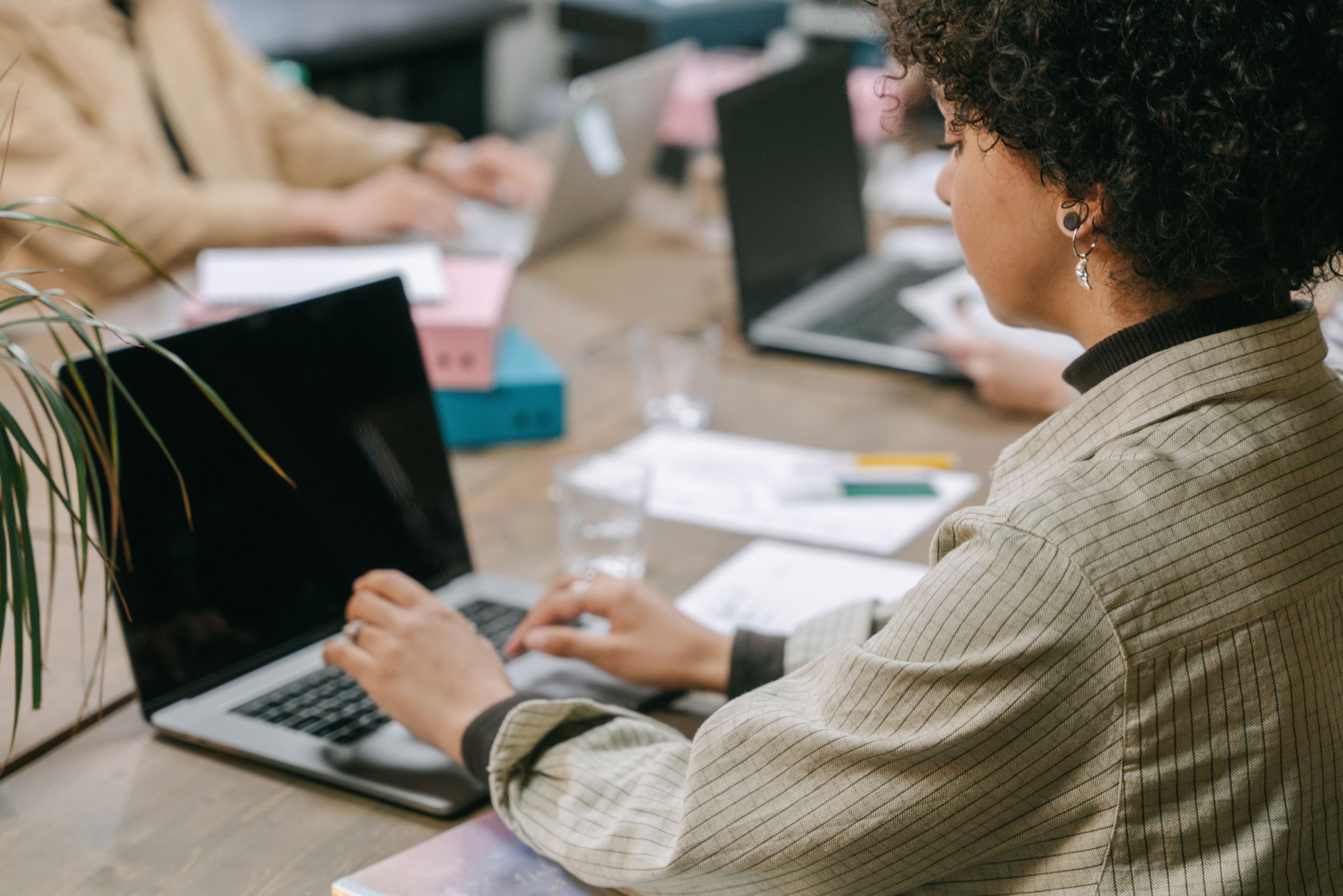 Salariee assise au bureau tapant sur un ordinateur portable, posture statique propice a la lombalgie a Issy-les-Moulineaux.