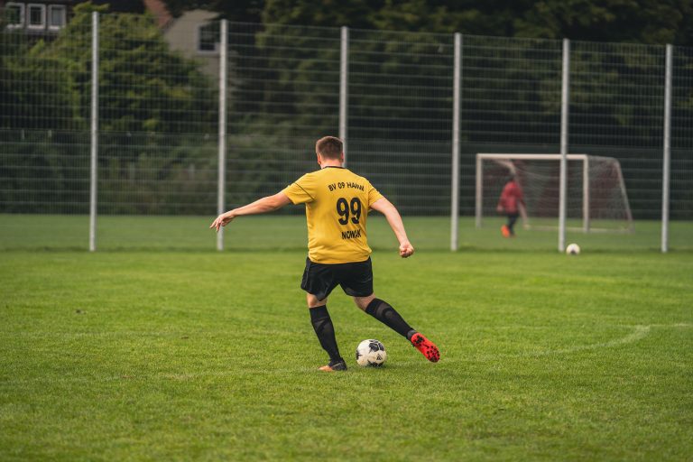 Footballeur amateur en maillot jaune frappant le ballon, geste a risque de pubalgie suivi a Boulogne 2 (Pau Casals).