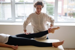 Kinesitherapeute mobilisant la cheville d'une patiente allongee, evaluation du tendon d'Achille a Issy-les-Moulineaux