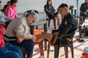 Kinesitherapeute palpant la cheville d'un jeune footballeur assis en bord de terrain.