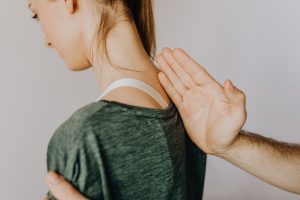 Kinesitherapeute palpant la base de la nuque d'une patiente de profil, evaluation cervicale a Courbevoie.