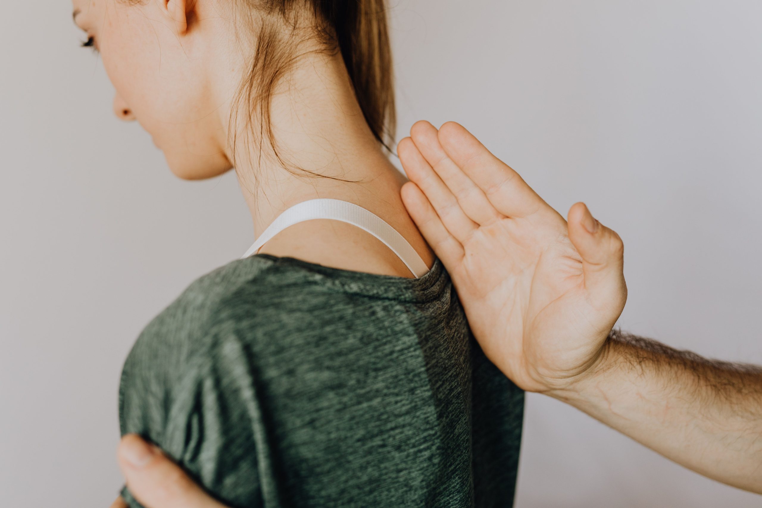 Kinesitherapeute palpant la base de la nuque d'une patiente de profil, evaluation cervicale a Courbevoie.